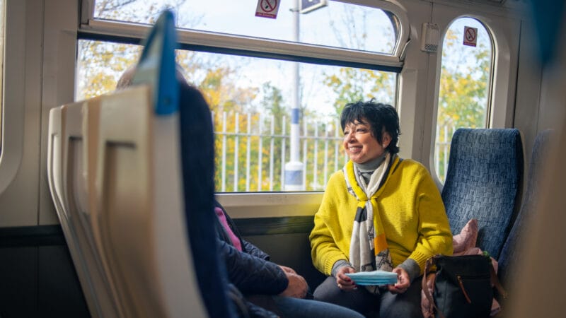 A smiling person sitting on a train
