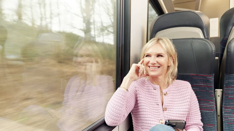Jo Whiley smiling while sitting on a moving train