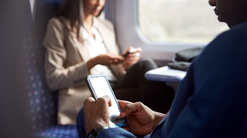 Business man and woman using a phone in a train carriage
