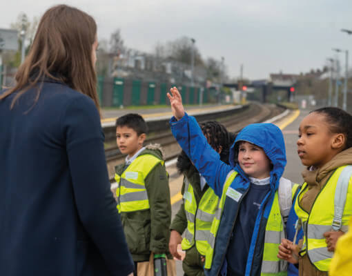 Children on a school trip at a train platform with a teacher