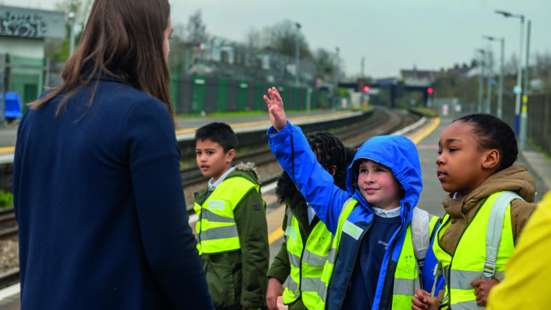 Children on a school trip at a train platform with a teacher
