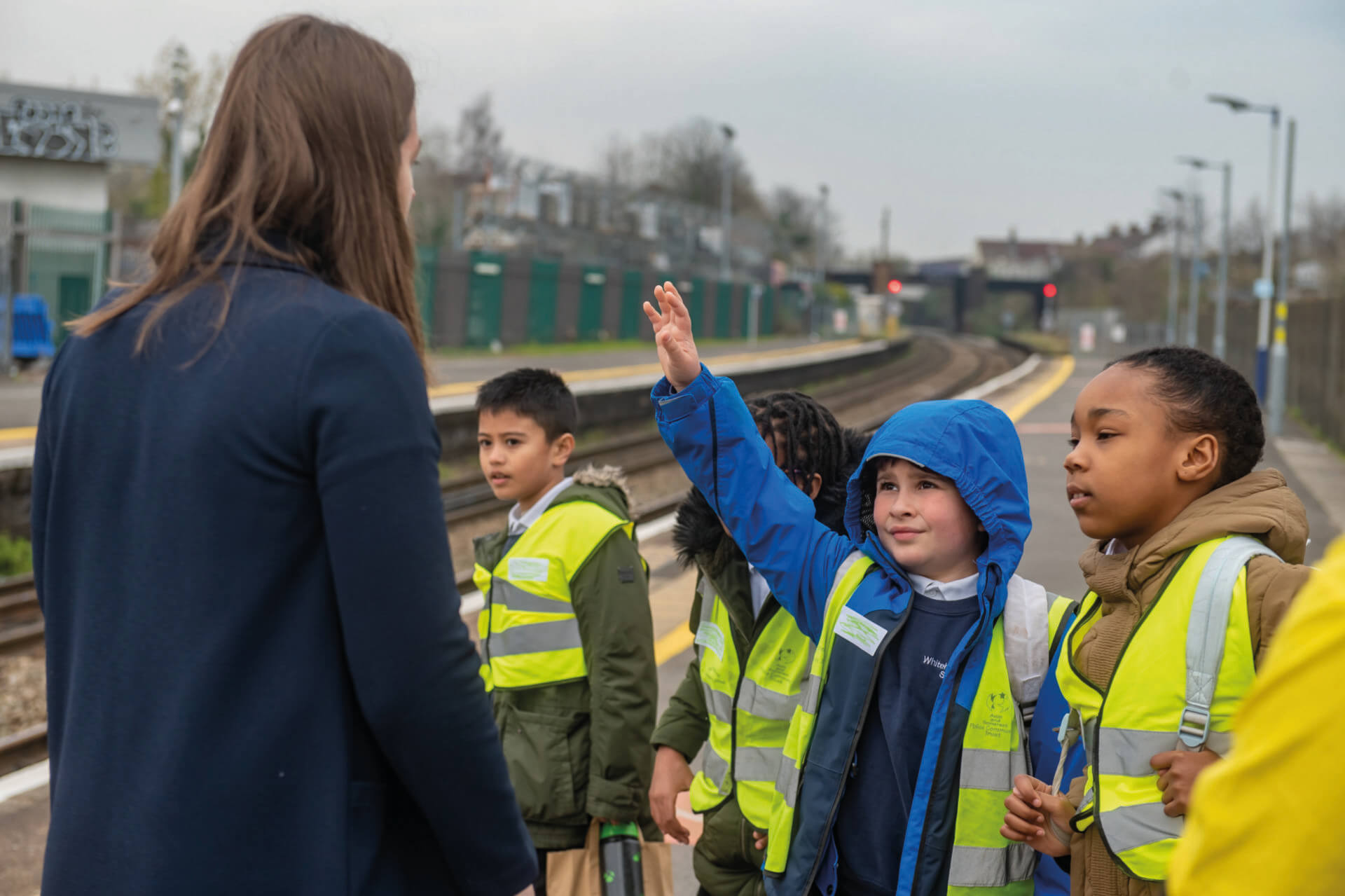 Children on a school trip at a train platform with a teacher