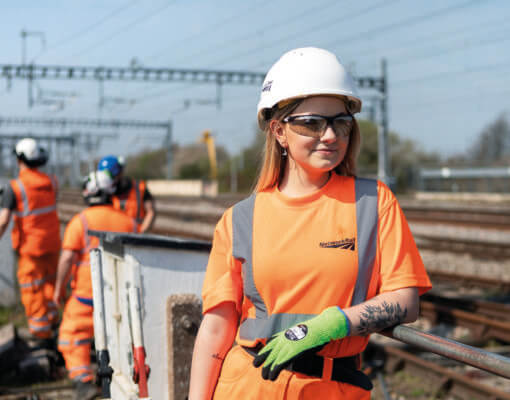 A female Network Rail worker wearing a hard hat and uniform