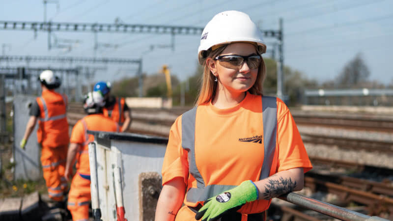 A female Network Rail worker wearing a hard hat and uniform