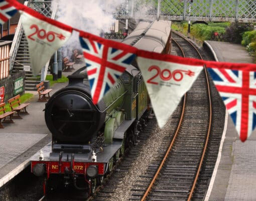 Banner of British Union Jack flag hanging in a train station alongside a steam train