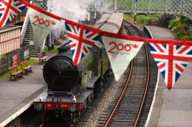 Banner of British Union Jack flag hanging in a train station alongside a steam train