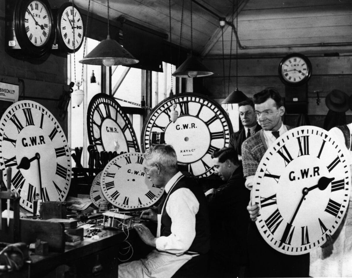 A group of employees at the Great Western Railway's signal works holding huge GWR clocks