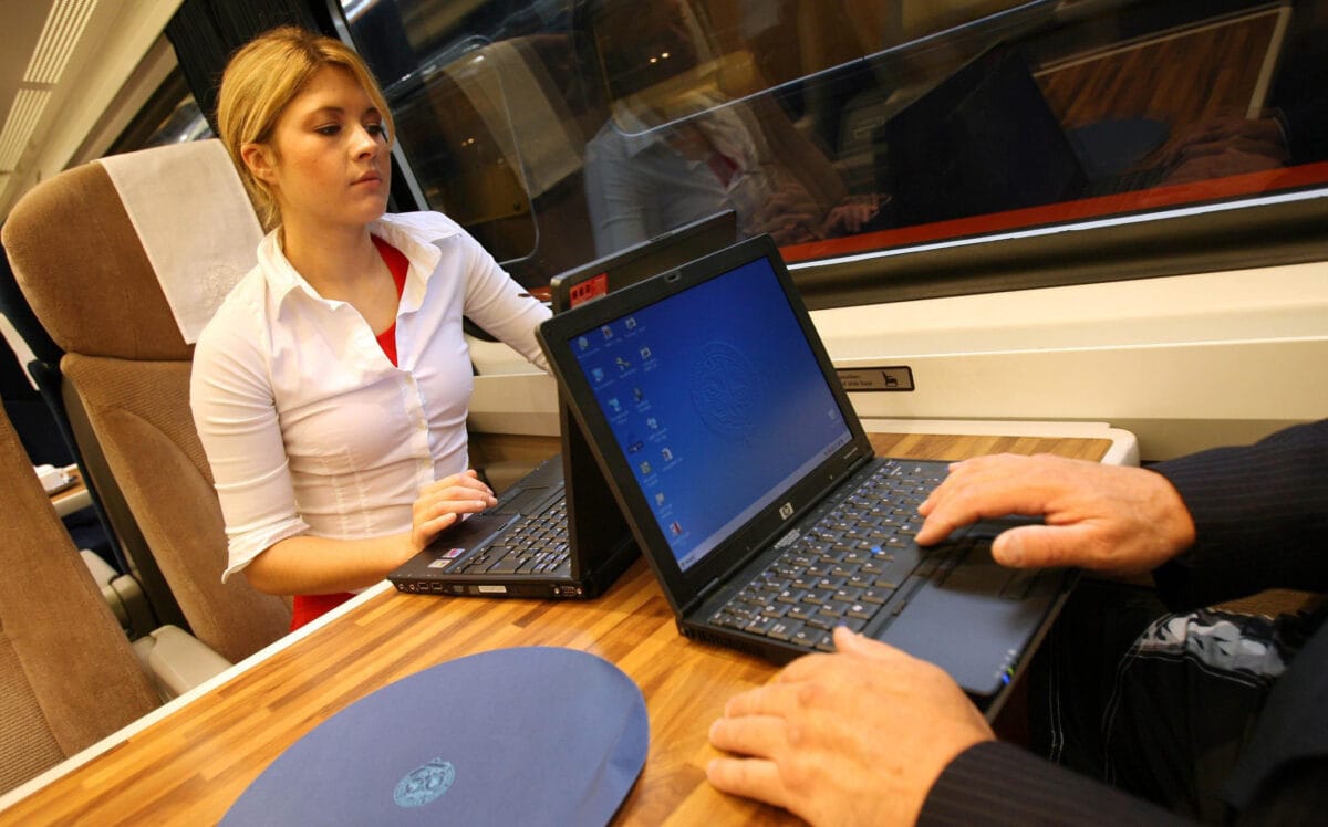 Two people using laptops on board a GNER train