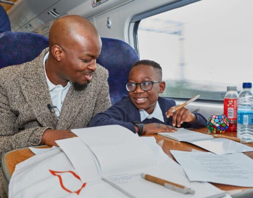 Man and young boy seated on train at table