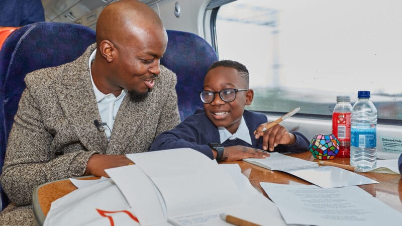 Man and young boy seated on train at table