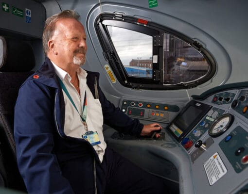 An Avanti West Coast trainee train driver sitting in a train's cab