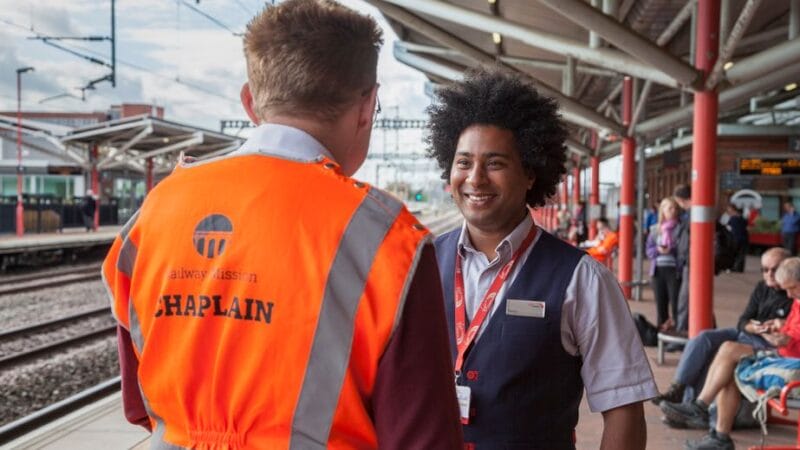 A photo of a Railway Mission chaplain talking to a member of rail staff on a platform