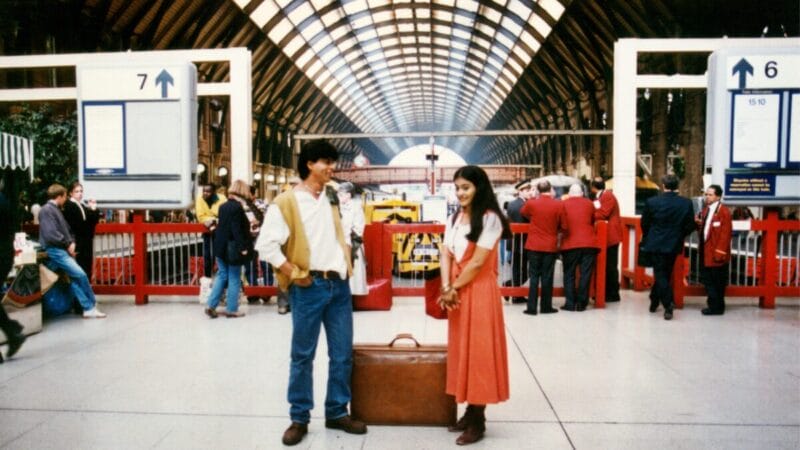 A man and a woman are standing opposite each other, smiling, at King's Cross train station