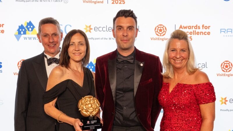 Foto: VisitEngland A group of award winners smiling and posing with their trophy on stage at a gala ceremony.