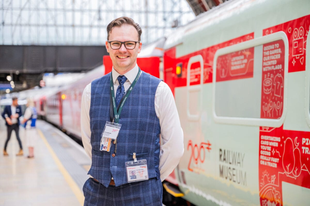 Llun: Jack Boskett A man, smiling, standing in front of a train