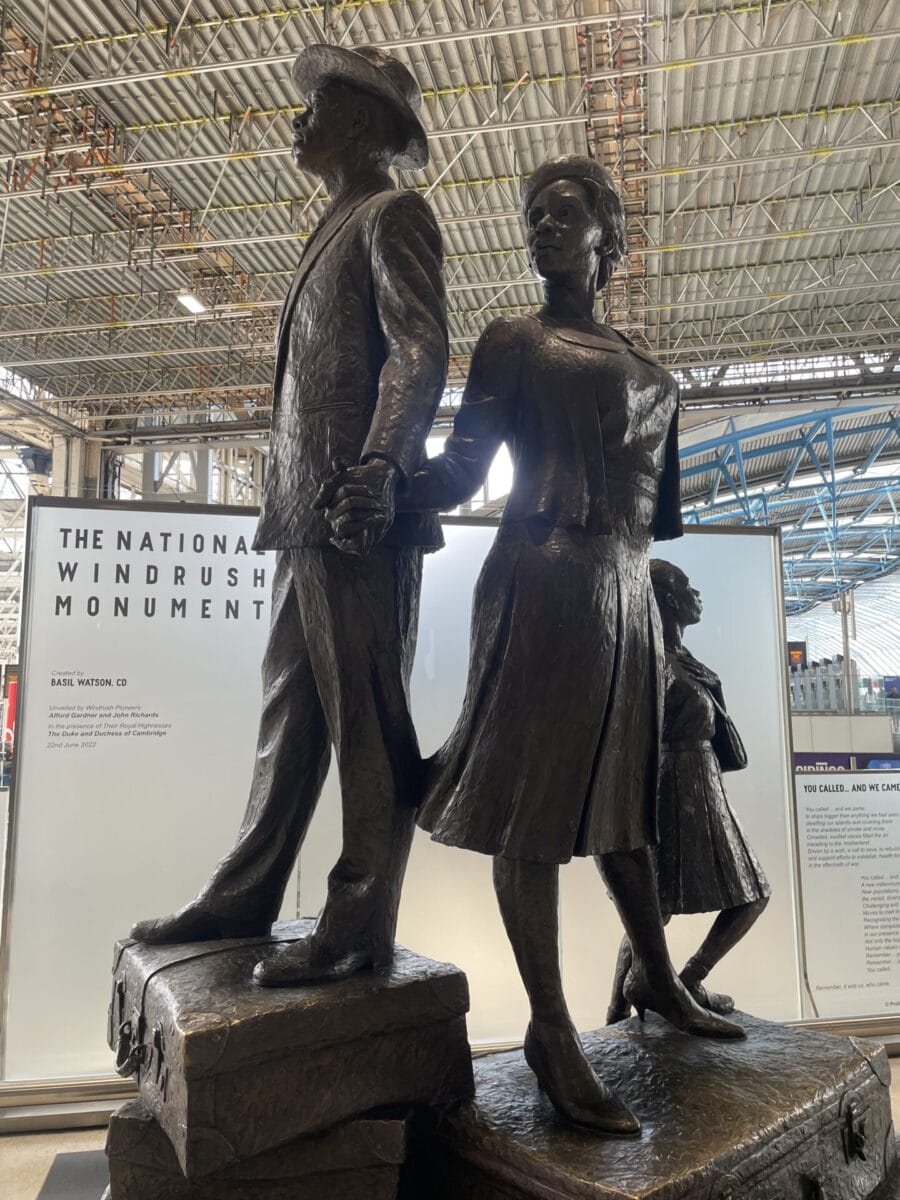 A statue of a man and a woman holding hands, standing on suitcases